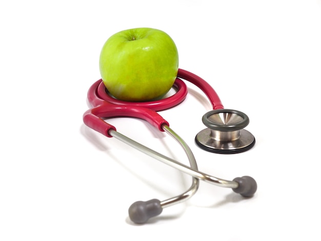 Stetoskop i świeży zielony jabłko na białym tle. Zdrowa koncepcja żywności i stylu życia.