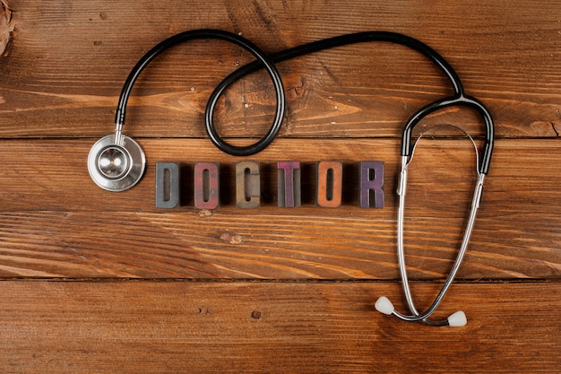 Stetoskop w drewnie i słowo lekarz w typ typografii