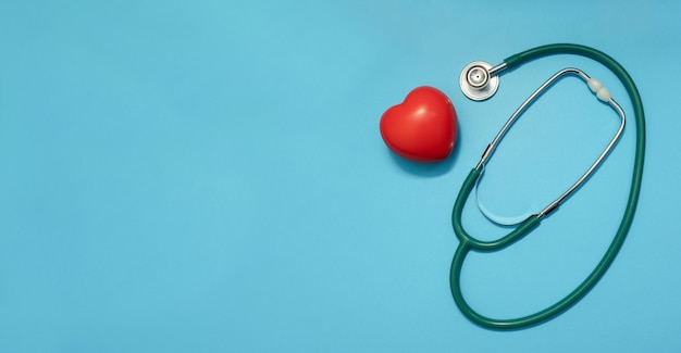 Stetoskop z czerwonym sercem na niebieskim tle Choroby serca Koncepcja dzień lekarzy i medycyna