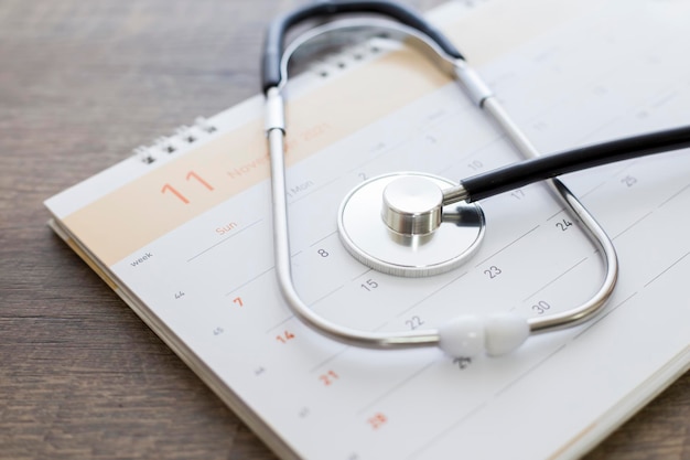 Stetoskop z datą na stronie kalendarza na drewnianej podłodze. Pojęcie opieki zdrowotnej.