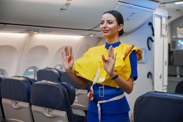 Stewardesa pokazuje zasady bezpieczeństwa przed lotem w wieczornym salonie samolotu