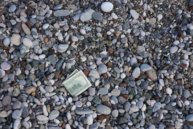 Sto dolarów do połowy pokryte okrągłymi kamieniami leży na plaży?