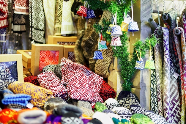 Stoisko z ozdobnymi szalikami, czapkami, skarpetami, rękawiczkami i małymi dekoracjami wystawionymi na sprzedaż na jarmarku bożonarodzeniowym w Rydze na Łotwie. Targ odbywa się co roku w grudniu.