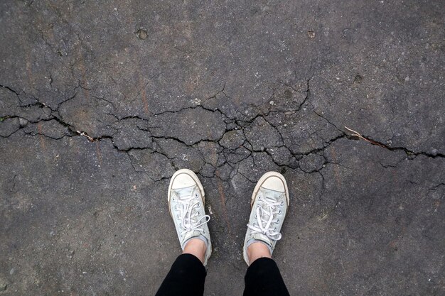 Zdjęcie stoję ze swoimi starymi butami na drodze uszkodzonej przez trzęsienie ziemi.