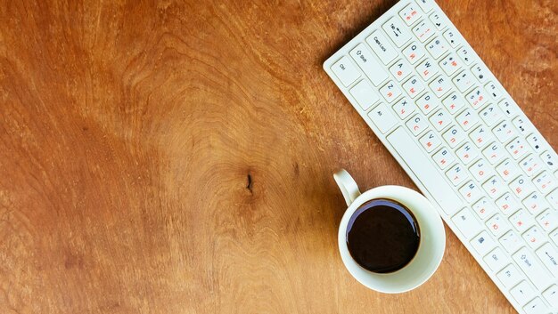 Stół biurowy z komputerem, zapasami i filiżanką kawy. klawiatura do kawy