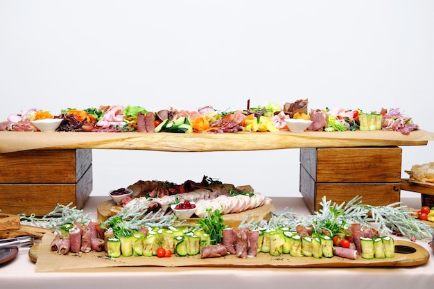 Stół bufetowy z zimnymi przystawkami Przekąski mięsne i warzywne ustawione są na drewnianych podstawkach