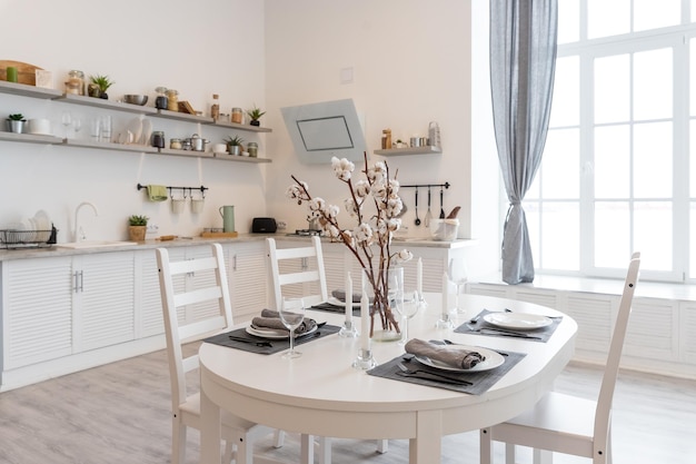 Stół do jadalni z białymi talerzami w nowoczesnym domu gałązki bawełny są w wazonie przytulna kuchniapiękna