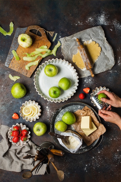 Stół kuchenny z jabłkami, mąką, masłem, truskawkami i cytryną