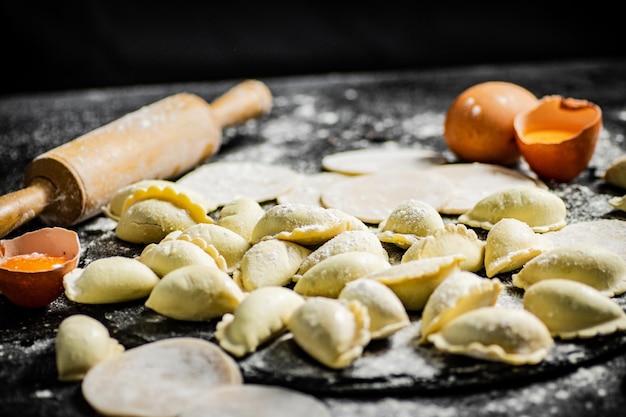 Stół pełen pierogów z wałkiem do ciasta i jajkami na nim