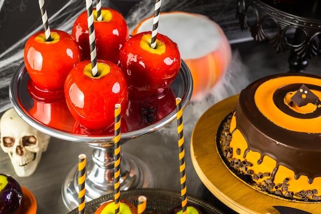 Stół z kolorowymi jabłkami cukierków i ciastem na imprezę Halloween.