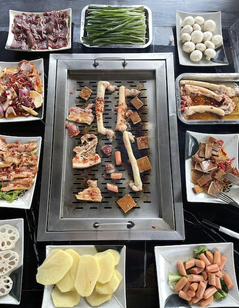 Stół z różnymi potrawami, w tym grillem, w tym różnymi mięsami, w tym różnymi warzywami i mięsami.