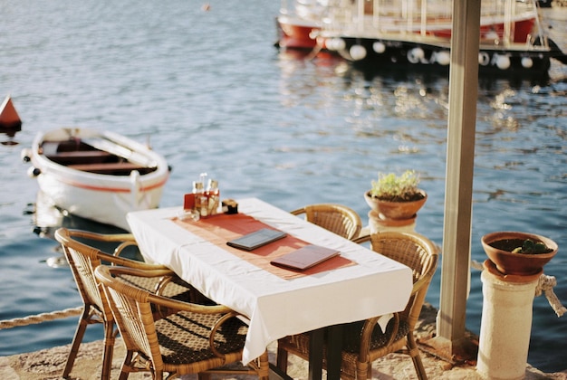 Stół z wiklinowymi krzesłami na molo w pobliżu zacumowanych łodzi