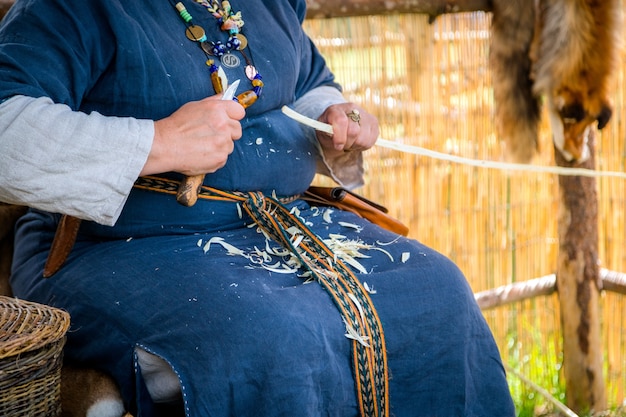 Zdjęcie stolarz kobiety ubrany w wiejską odzież i rzeźbiący drewniany kij