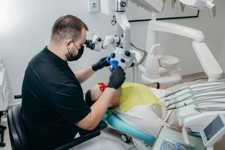 Stomatolog badający zęby pacjenta za pomocą nowoczesnego mikroskopu