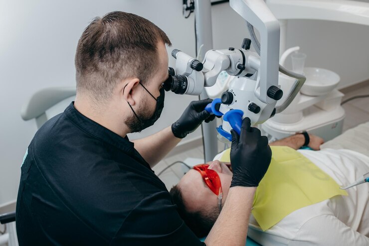 Stomatolog badający zęby pacjenta za pomocą nowoczesnego mikroskopu