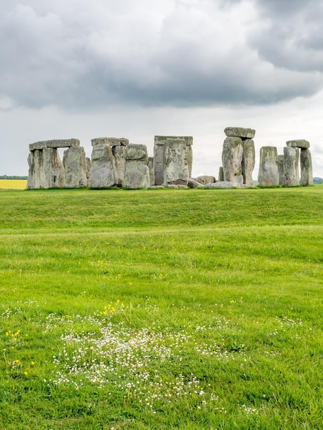 Stonehenge z nierozpoznanym turystą w pobliżu Salisbury w Anglii pod zachmurzonym niebem