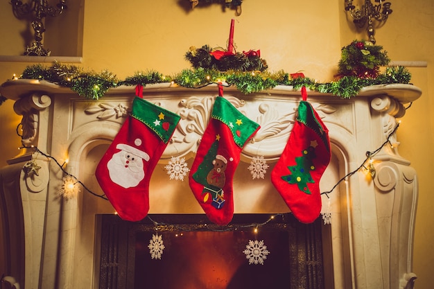 Stonowane zdjęcie trzech czerwonych świątecznych skarpet wiszących na kominku w domu