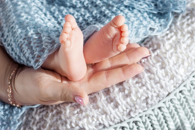 Stopy dziecka w rękach matki. Małe stopy noworodka na kobiece dłonie zbliżenie. Mama i jej dziecko. Piękny koncepcyjny obraz macierzyństwa
