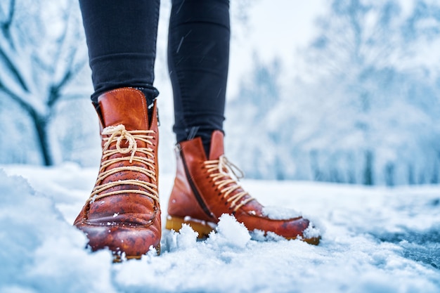 Stopy kobiety na zaśnieżonym chodniku w brązowych butach