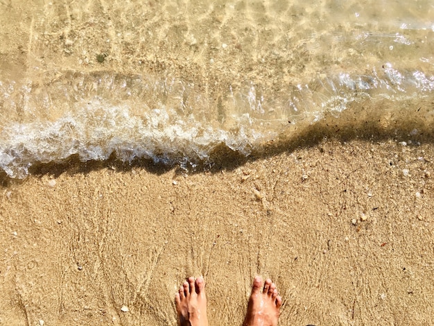 Zdjęcie stopy na piaszczystej plaży i miękkiej fali