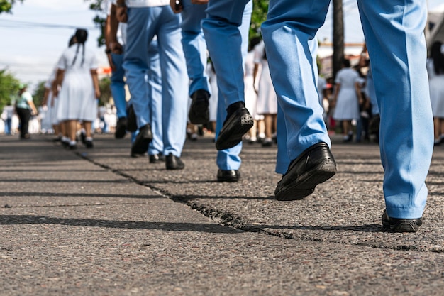 Stopy umundurowanych mężczyzn i kobiet maszerujących w paradzie na ulicy