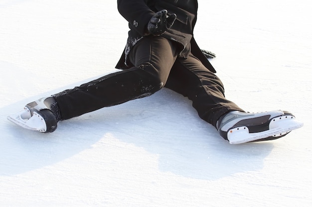 Stopy w łyżwach upadłego mężczyzny na lodowisku