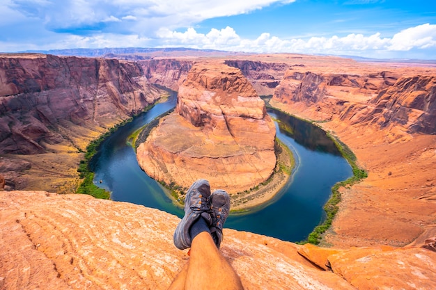 Stopy ze skrzyżowanymi nogami odpoczywają, oglądając Horseshoe Bend i rzekę Kolorado w tle, Arizona. Stany Zjednoczone