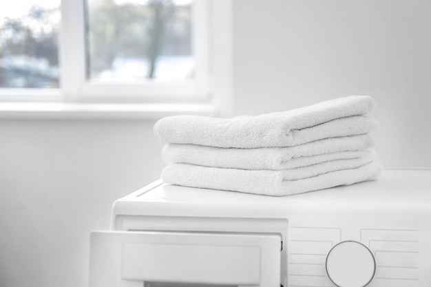 Stos czystych ręczników na pralce w pralni samoobsługowej