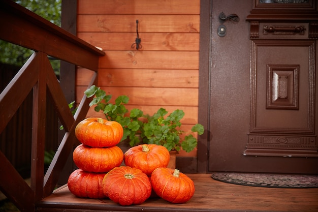 Stos dużych pomarańczowych dyni W pobliżu drzwi domu. Jesienne żniwa i wystrój domu na Halloween. Skopiuj miejsce