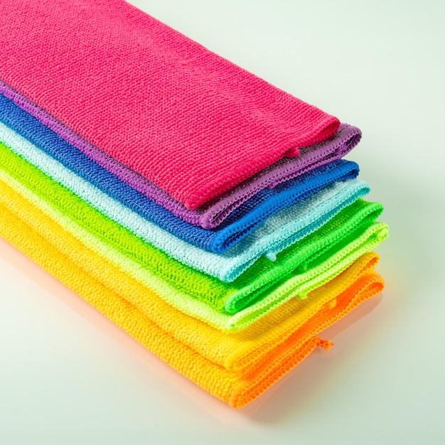 Stos kuchennych ręczników z mikrofibry w jasnych kolorach na jasnym lustrzanym tle