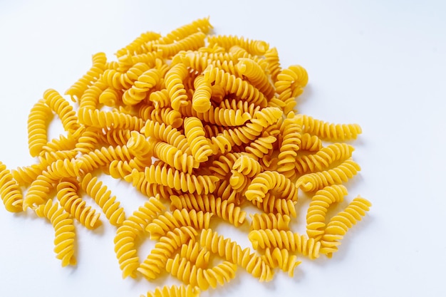 stos makaronu spirali rozrzucone na jasnym tle. makaron spiralny w kształcie korkociągu lub makaron fusilli