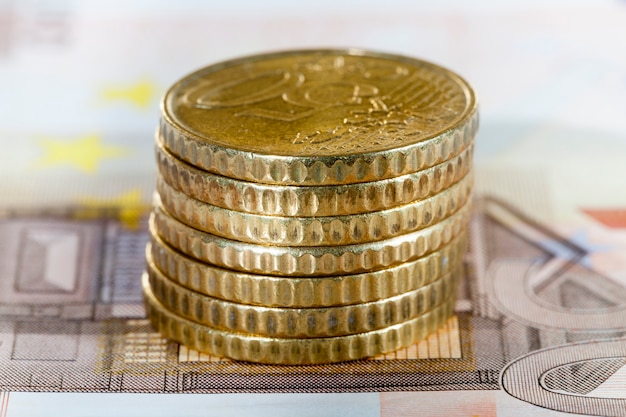Stos monet europejskich o wartości pięćdziesięciu euro, leżący na banknocie dziesięciu euro, zbliżenie gotówki