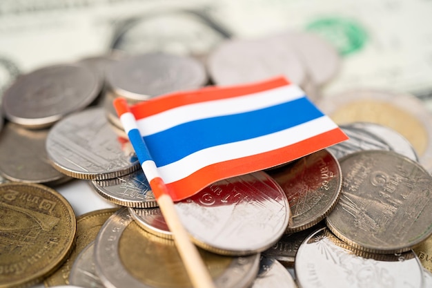 Stos monet z flagą Tajlandii na białym tle.