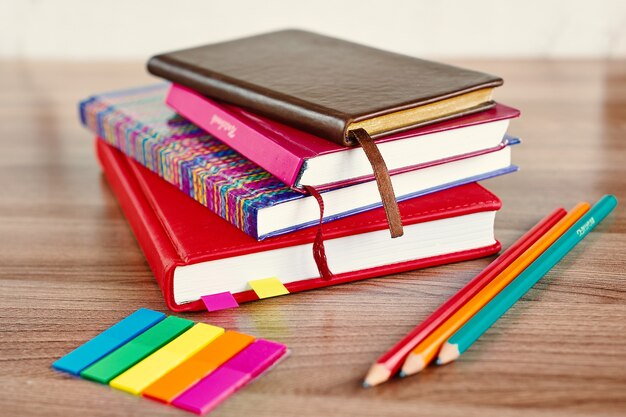 Stos notesów z ołówkami i kolorowymi zakładkami na drewnianym stole