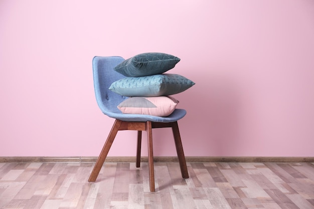 Zdjęcie stos poduszek na krześle w pobliżu kolorowej ściany