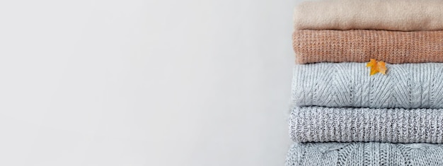 Stos przytulnych swetrów z dzianiny na neutralnym tle Ciepła koncepcja