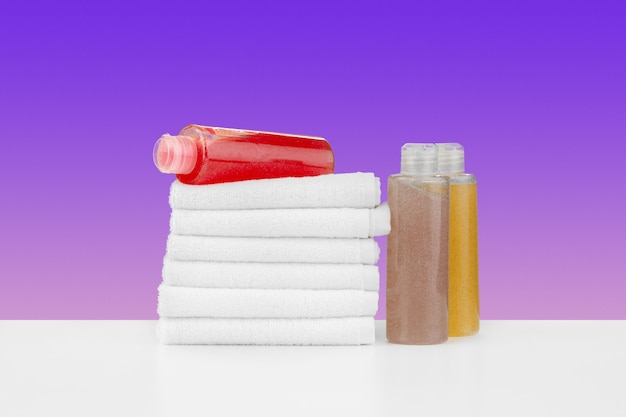 Stos ręczników butelek z szamponem na białym stole