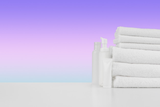 Stos ręczników butelek z szamponem na białym stole
