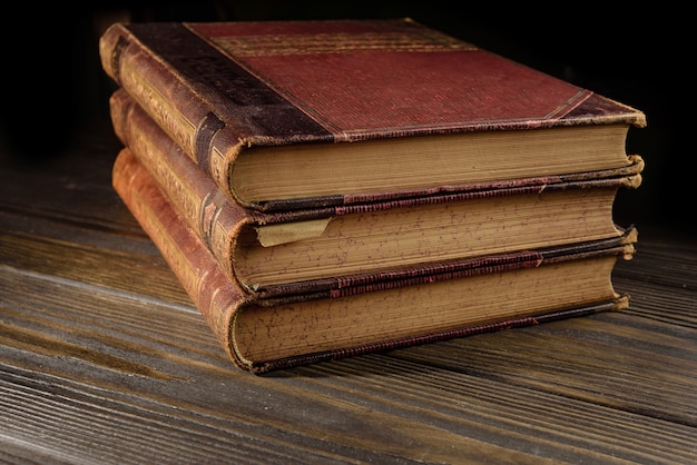 Stos starych książek leżących na drewnianym stole