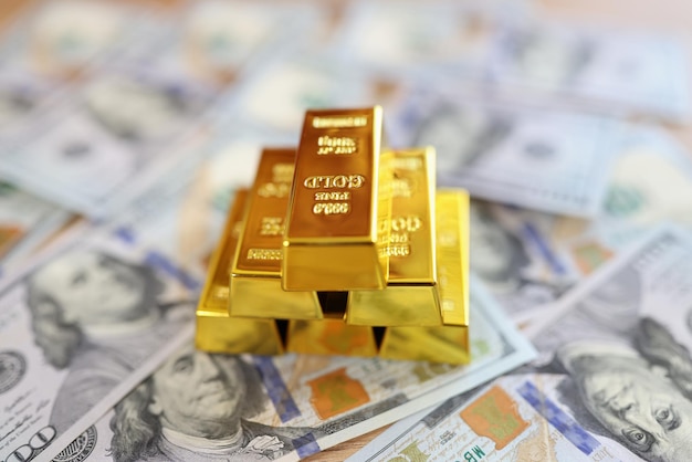 Stos sztabek złota leży na banknotach dolarowych w bankowych oszczędnościach i akumulacji pieniędzy online