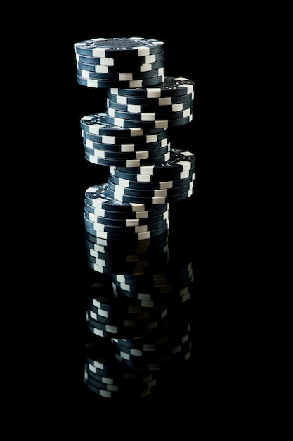 Stos żetonów do gry w kasynie na czarnym tle odblaskowym