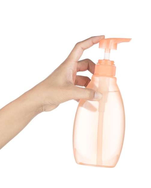 Stosowanie pomarańczowej butelki mydła w płynie na białym tle