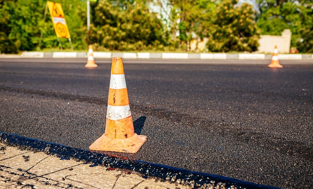 Stożki drogowe na drodze Duża warstwa świeżego gorącego asfaltu Budowa dróg