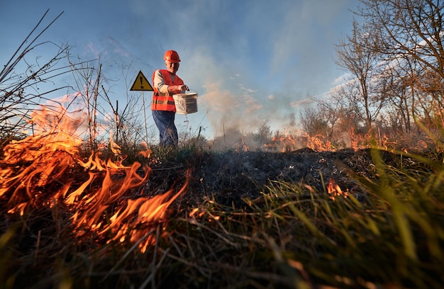 Strażak ekolog walczący z ogniem na polu wieczorem