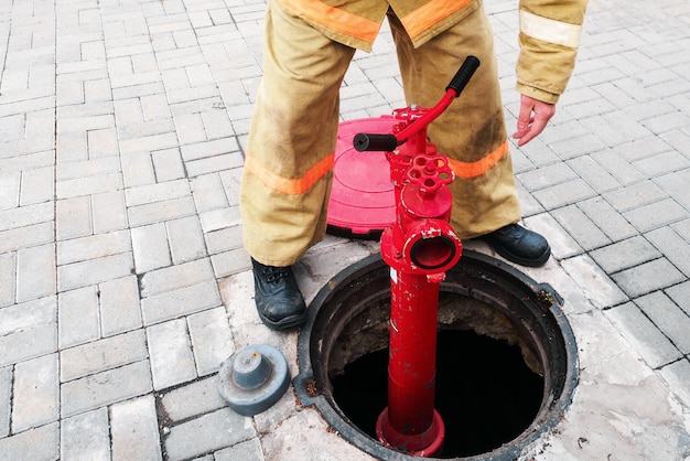 Strażak lub ratownik instaluje hydrant przeciwpożarowy w otwartej studni Praca strażaka w przypadku pożaru Szkolenie i ćwiczenia w przypadku pożaru Tło