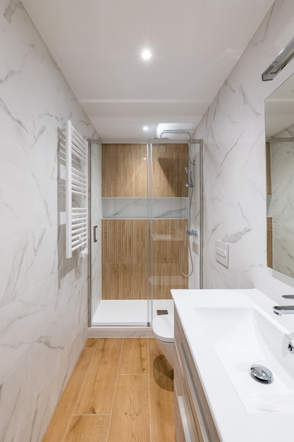 Strefa prysznica z drewnianym wykończeniem i szklanymi drzwiami wnętrza nowoczesnej odnowionej łazienki