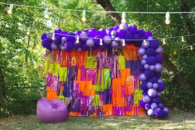 Zdjęcie strefa zdjęć urodzinowych w parku wielokolorowe serpentyny, balony i żarówki