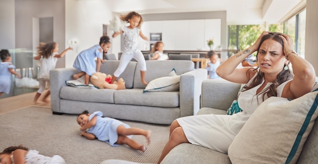 Stresowy ból głowy i matka z dziećmi z ADHD biegającymi, skaczącymi i bawiącymi się w rodzinnym domu lub salonie Wypalenie psychiczne lub niepokój rodzica z autyzmem i nadaktywnymi dziećmi