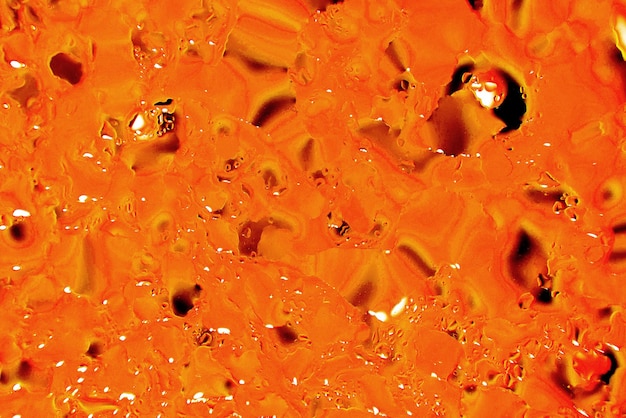 Streszczenie jasnopomarańczowe tło z bańkami oleju okrąża wodę z bliska