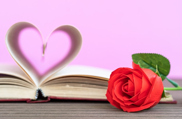 Strona książki o zakrzywionym kształcie serca i czerwonej róży